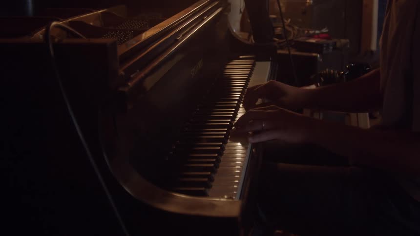 Male pianist with a t shirt plays piano indoors