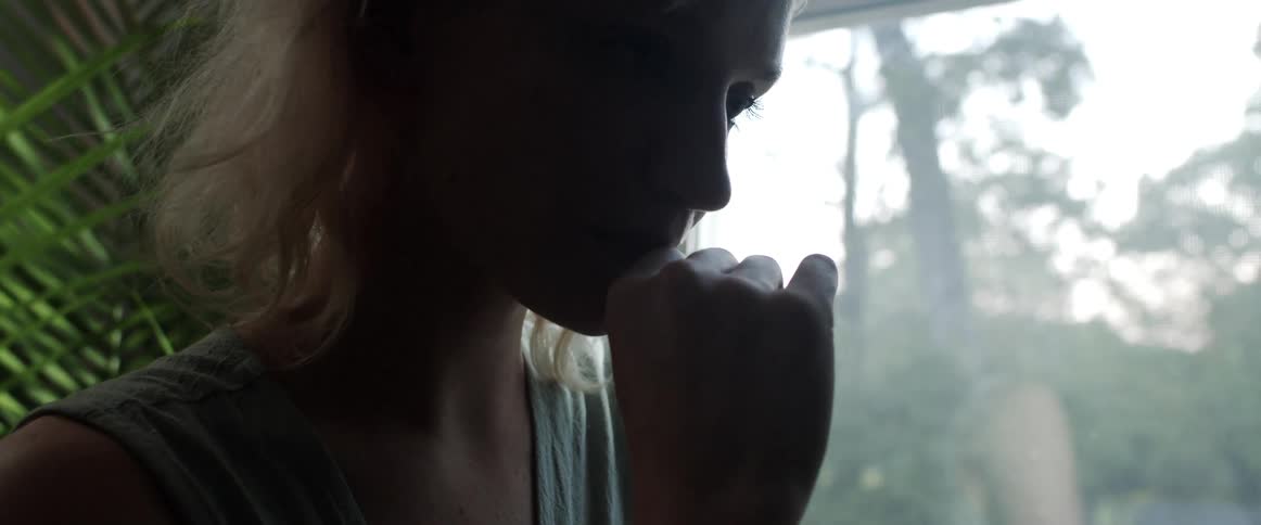 A woman is standing indoors next to a window in spring