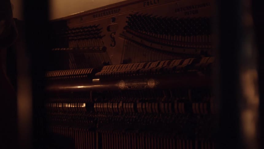 A man is playing the piano in the dark room