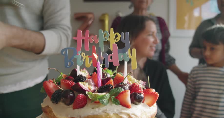 Woman ligth up a candle in a birthday cake in front of the guests