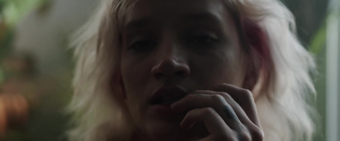 Blonde woman touching her lips looks at the camera