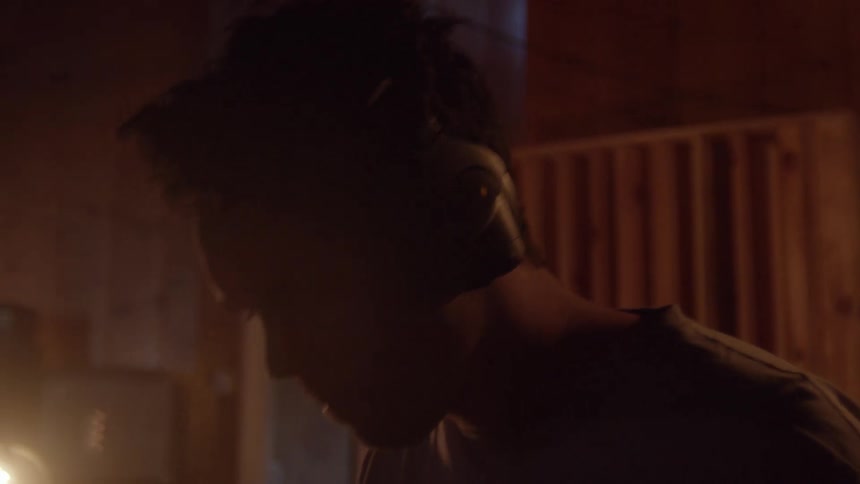 Silhouette of a young man wearing headphones playing drums inside a dimly lit room