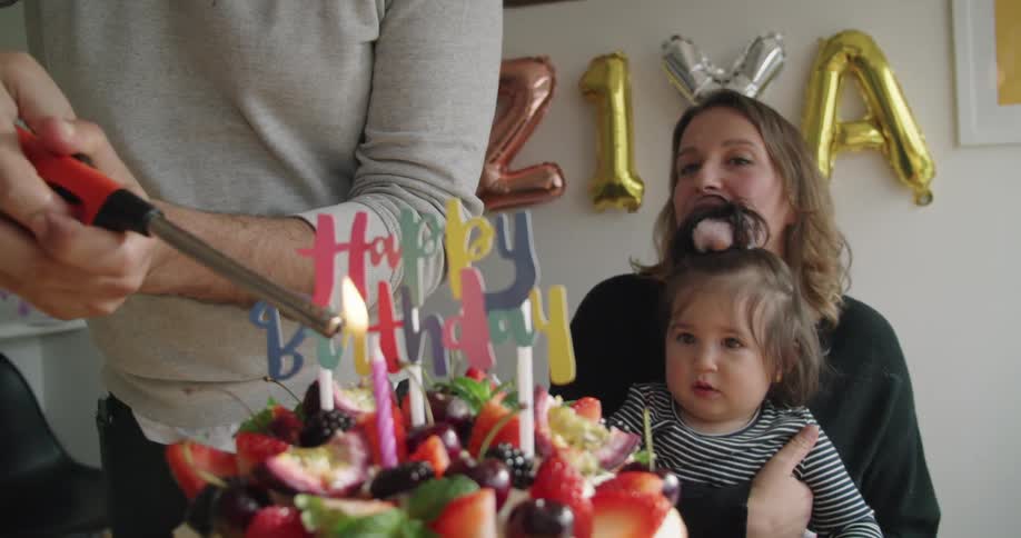 Woman ligth up a candle in a birthday cake in front of the guests