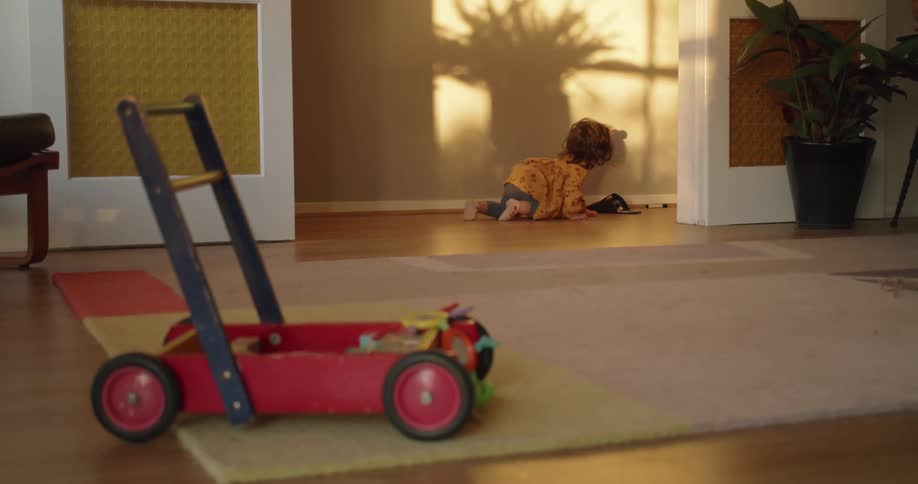 A toddler is crawling on the floor across a room
