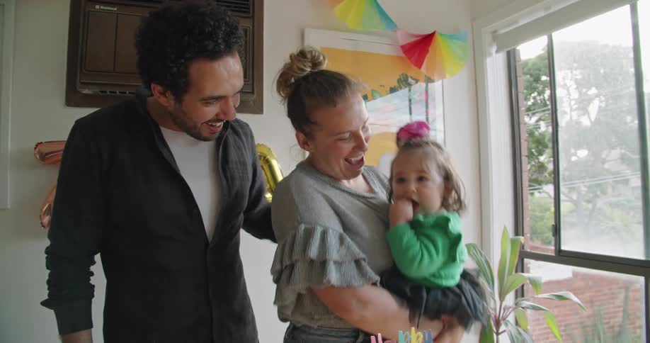 A man a woman and a little girl in a room with birthday decorations