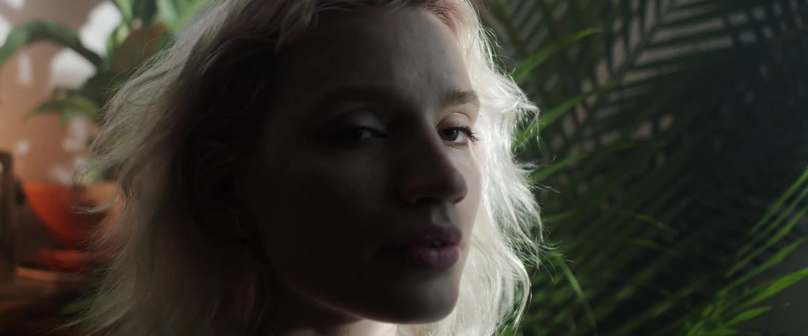 A woman is sitting indoors next to a plant