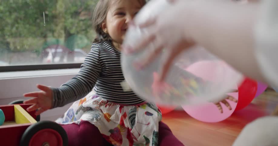 A child is playing with balloons while sitting indoors