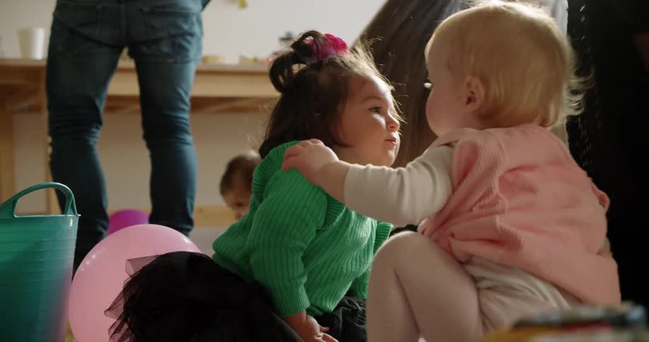 A group of baby girls sit together and try to play