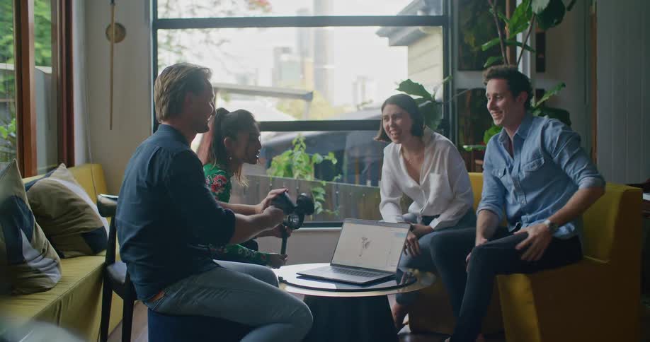 Group of people sitting in the living room gathered around a laptop working on a design