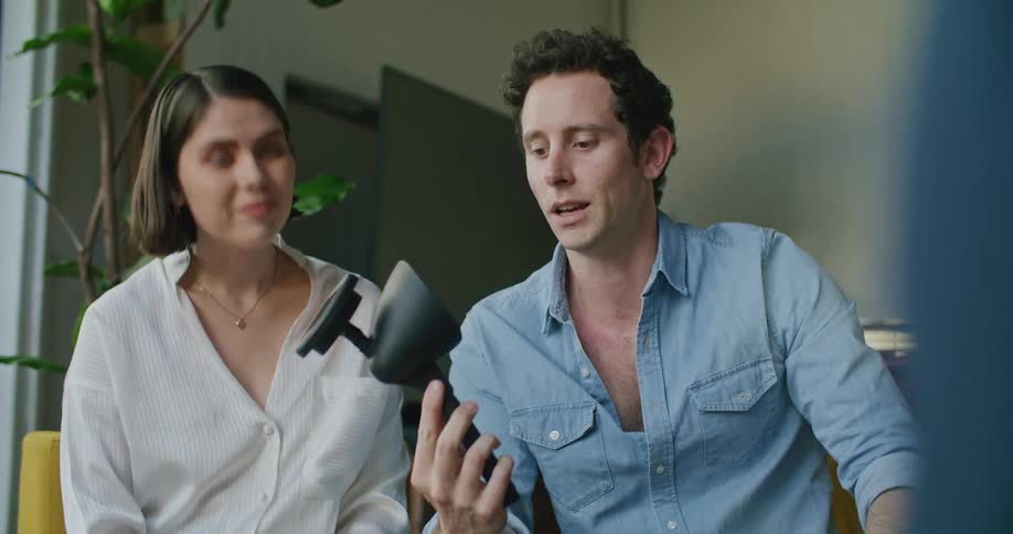 A man and a woman sitting on couches with a wall and door in the background