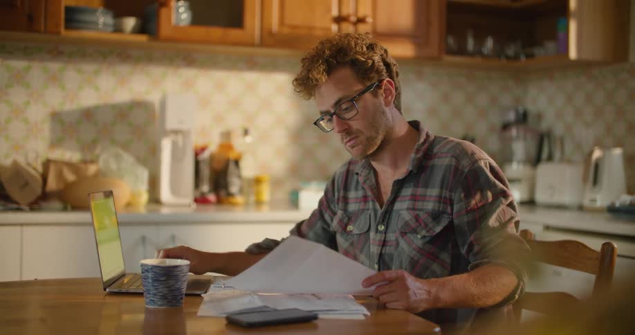 A man is working at his kitchen table in the morning