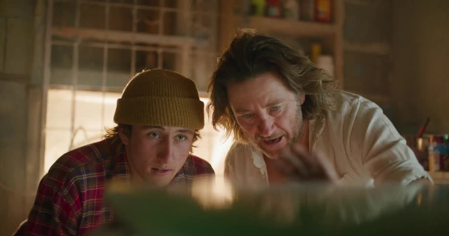 A man is talking with a teenager and showing him something