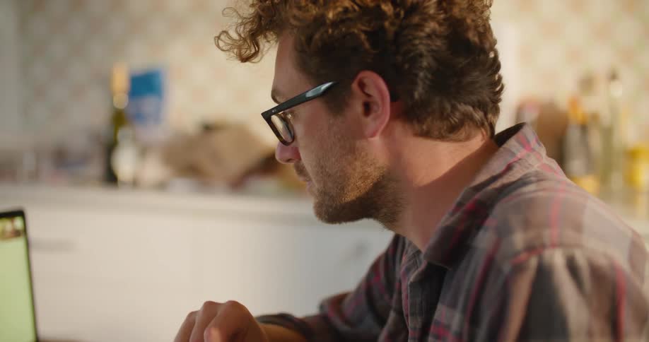 Men video conference via laptop as black furred dog walks past table