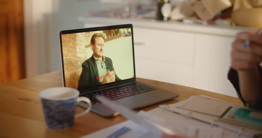 Two coworkers have a video call on a laptop