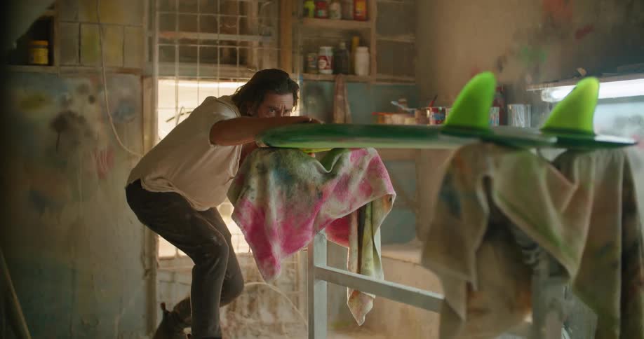 A man checking on a surfboard in a shop