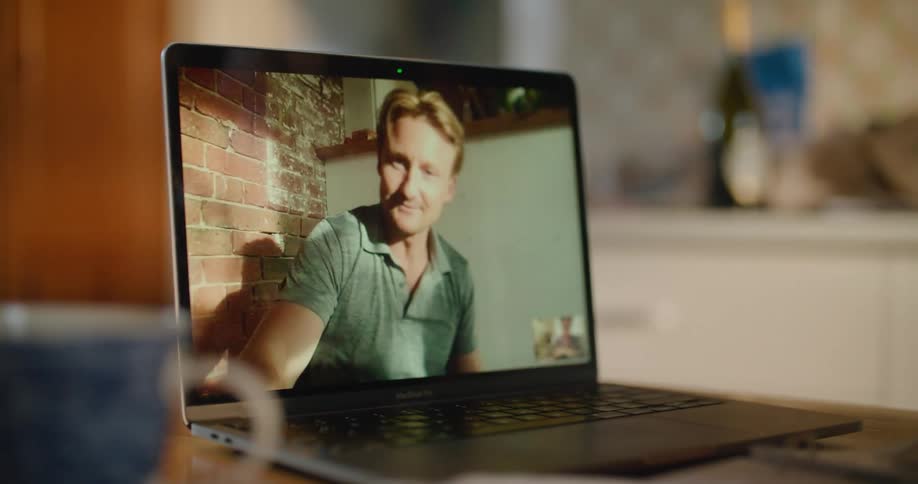 A person in a room using a laptop on a table with a mug