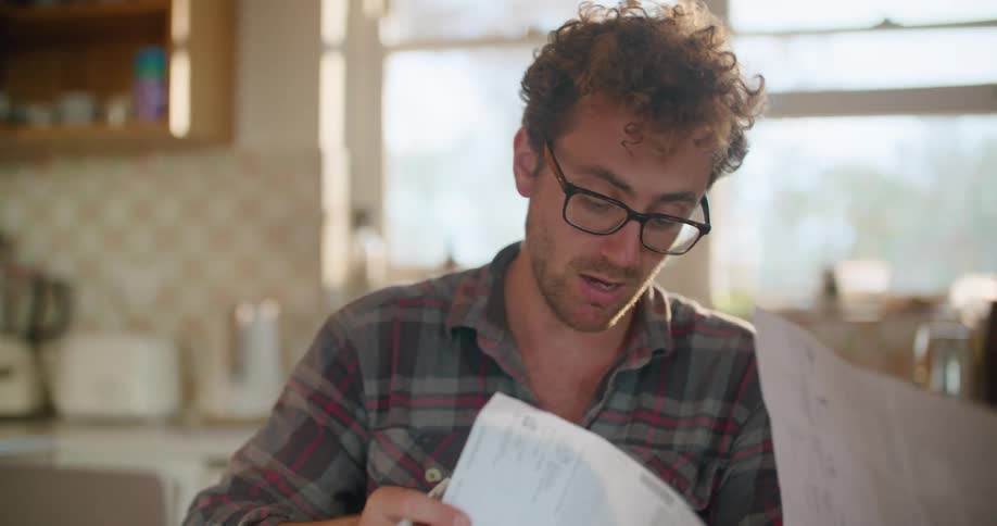 Man sitting in the kitchen table in the morning working on a laptop