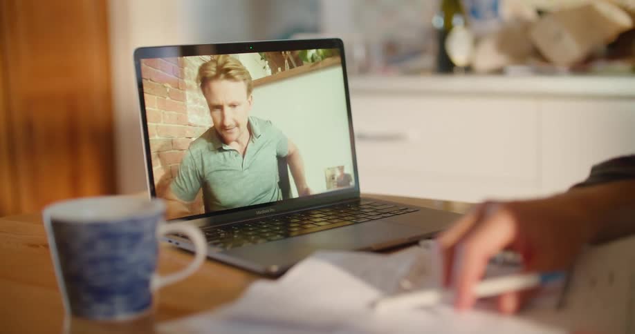 A man is talking and reading papers on the laptop
