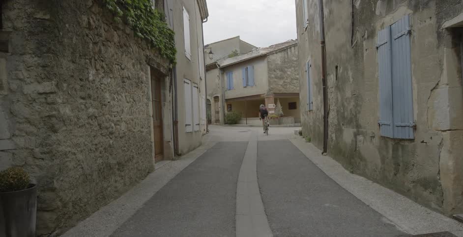 Cyclist riding through a village on a paved street