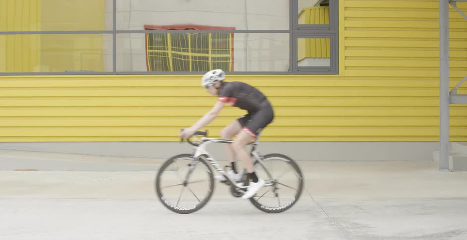 A man riding a bicycle past a yellow building