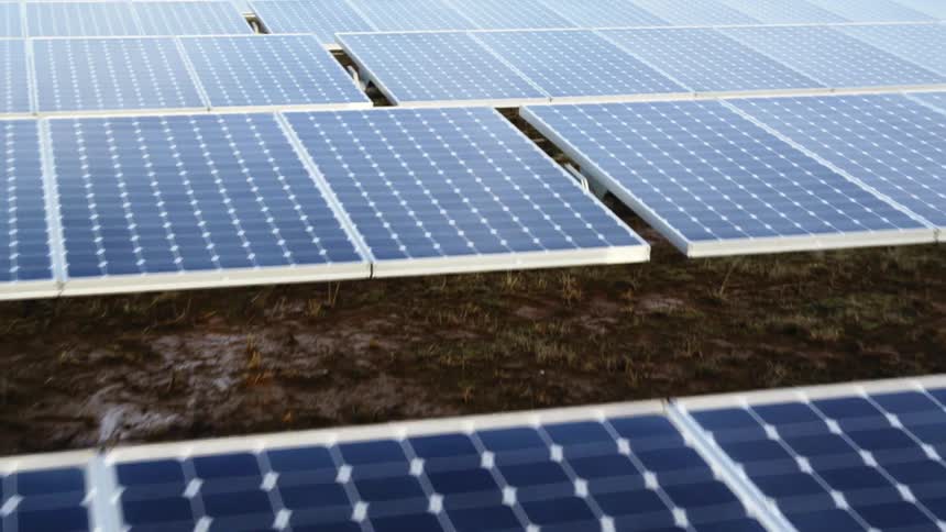 Low pullback over rows of solar panels as the morning light reflects from their surface