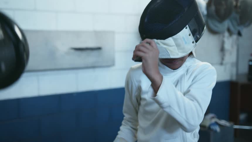 A boy is in a gym and learning how to fence
