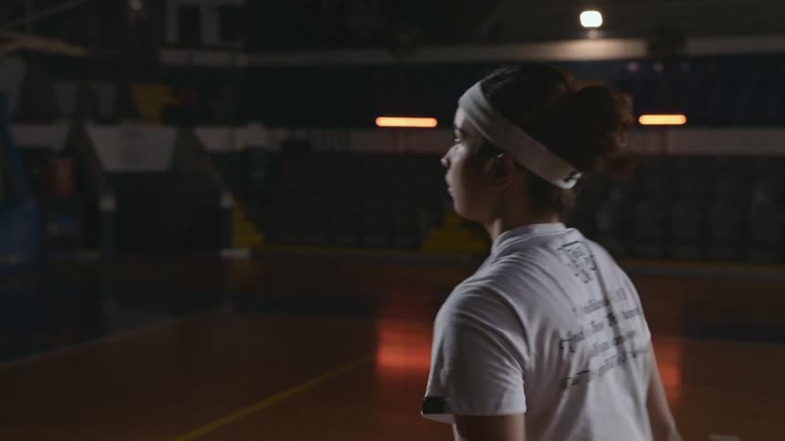 A teenager is playing basketball in a gym