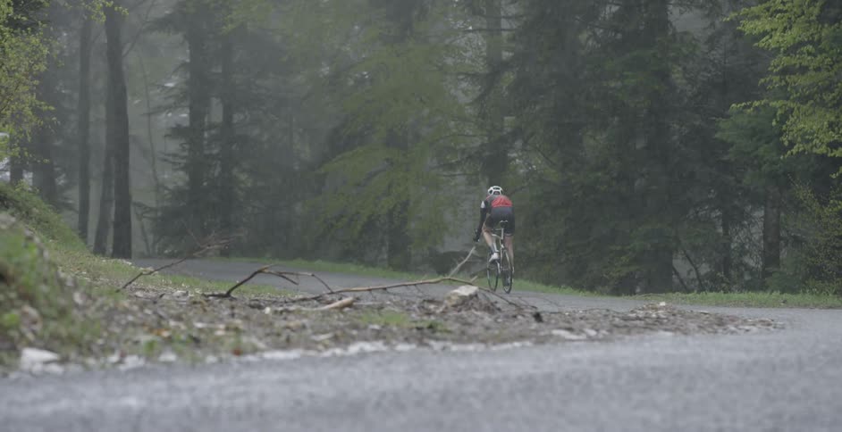 Person riding bicycle down road in the rain
