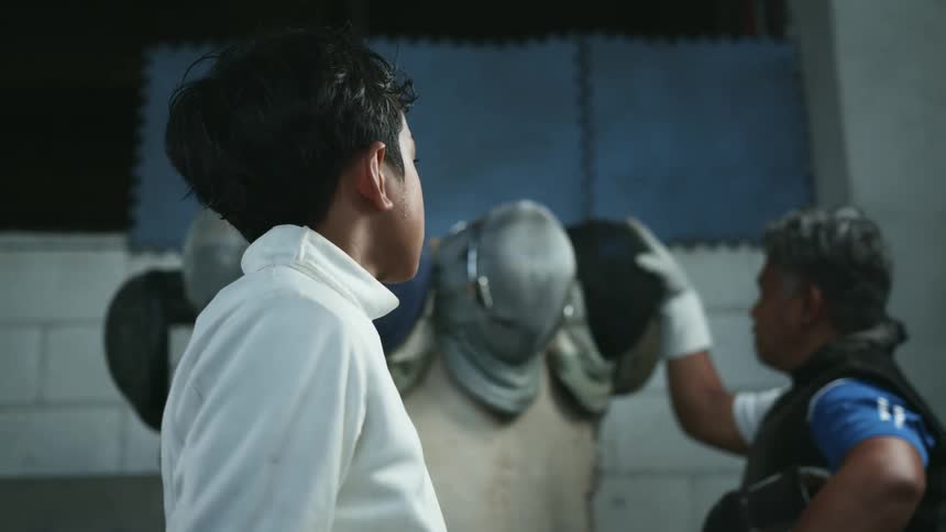 A man putting a helmet on a statue next to a boy