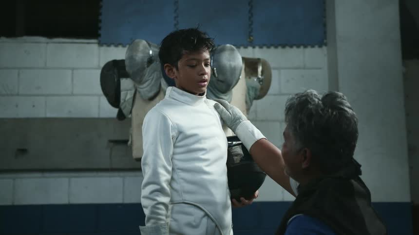 Coach talks to a girl wearing white fencing gear