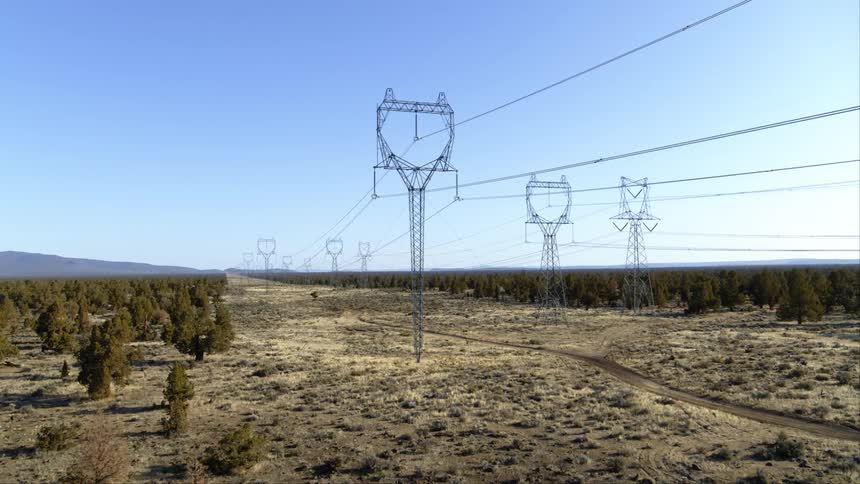 High voltage power lines from a solar power facility transmit electricity into the distance