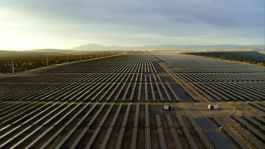Subtle orbit over a large solar power facility as sunlight reflects softly off the long rows of panels