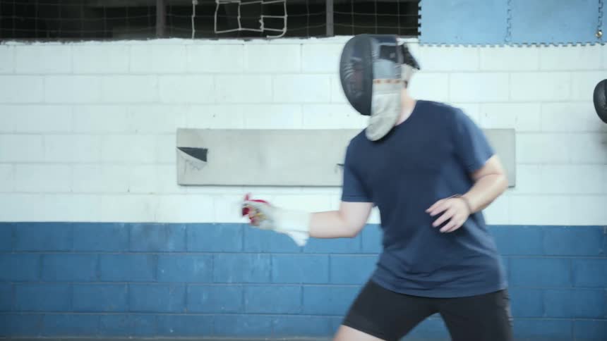 A man is practicing fencing in the gym