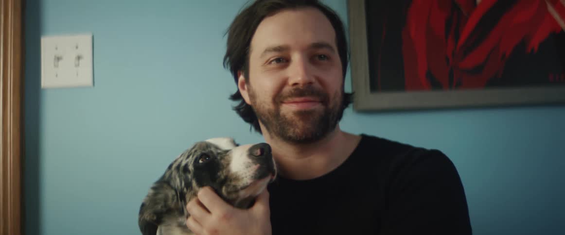 A man is sitting indoors and holding his dog