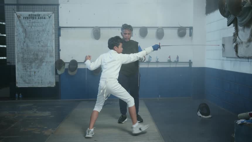 A man is teaching a boy a sport indoors