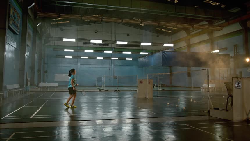 A female playing racquet ball inside a gym warehouse