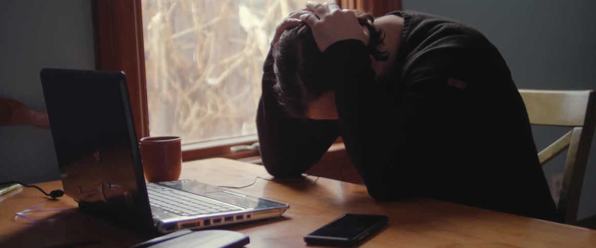 Anxious man nervously working on a laptop in a room
