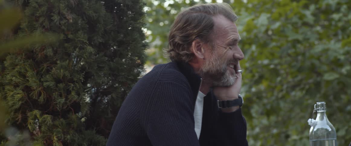 Couple talking and laughing sitting on a table in a park