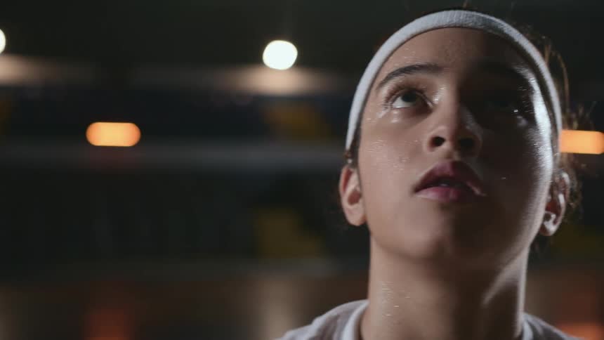 A teenager practices throwing lay ups with a basketball in a gym