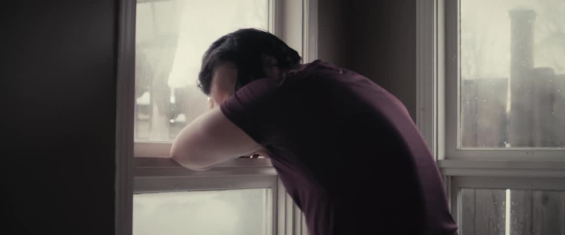 A man is sitting by the window and looks defeated