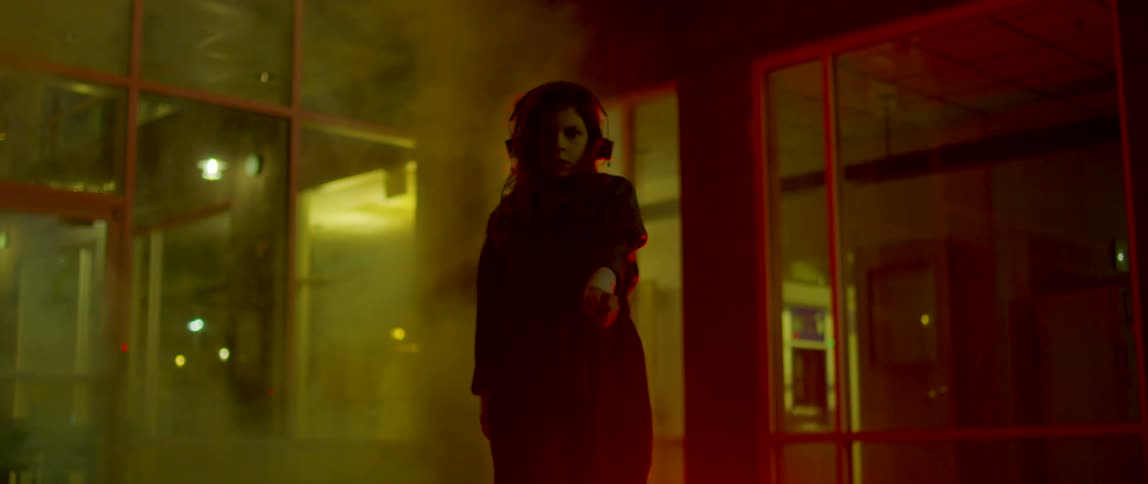 A woman in a room with smoke dancing with a door and windows in the background