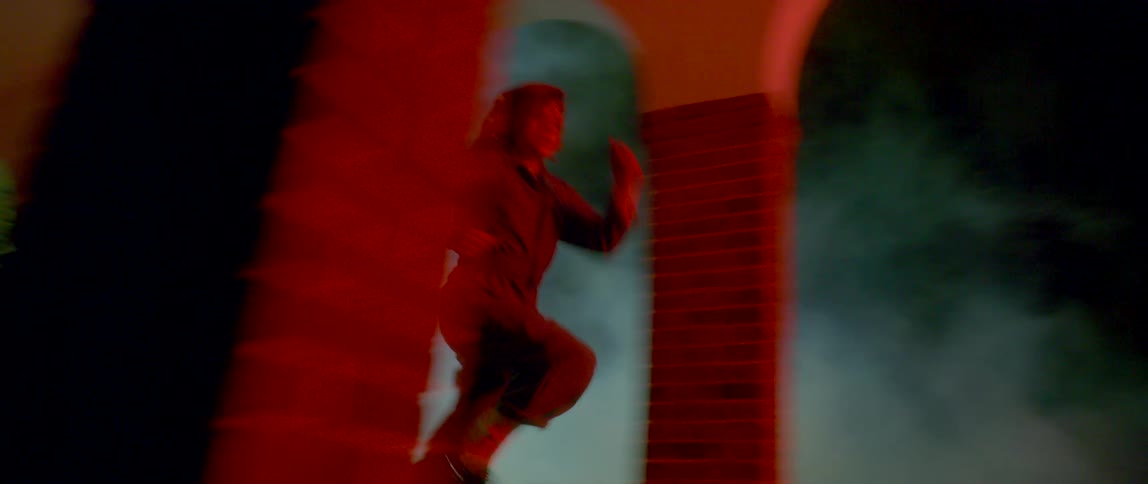 A woman with headphones running in a hallway with smoke with pillars and arches
