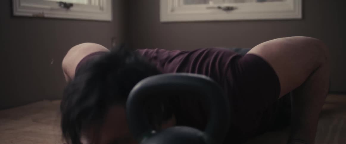 A man is working out inside of his room during the day