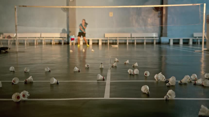 A female athlete is hitting shuttlecocks in the badminton court