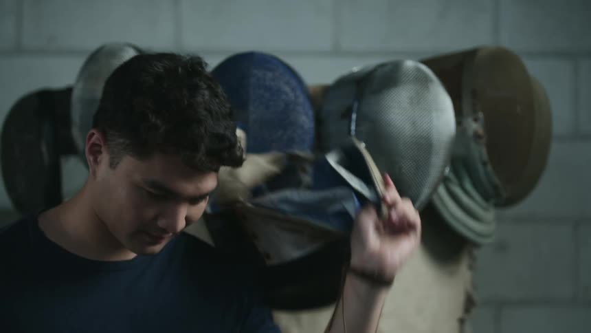 A man taking off a fencing helmet
