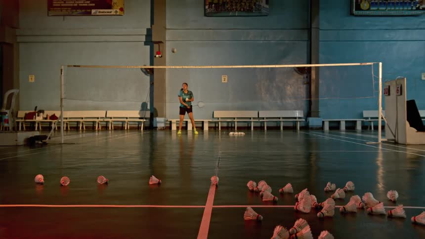 A badminton player practices serving over a badminton court net