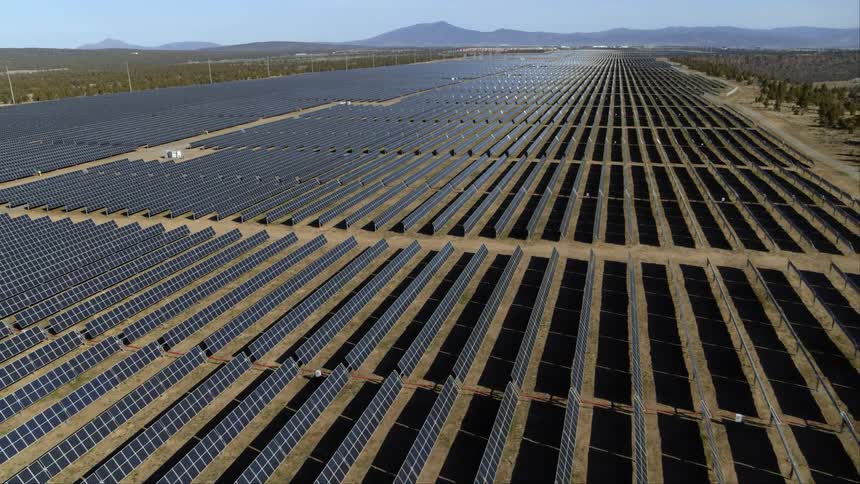 Pullback ascent over an enormous solar power farm that stretches to the horizon
