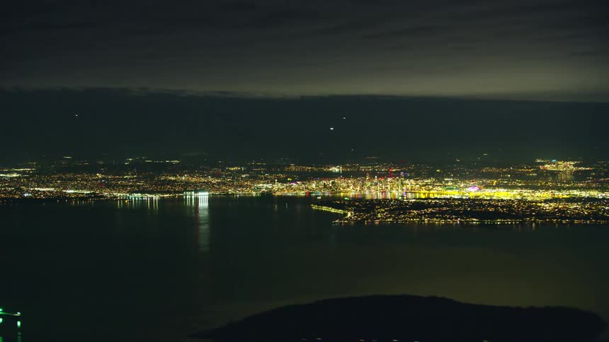 Night time lapse from an airplane at 10,000 feet looking east across the Puget Sound at downtown Seattle and the arriving air traffic and city lights