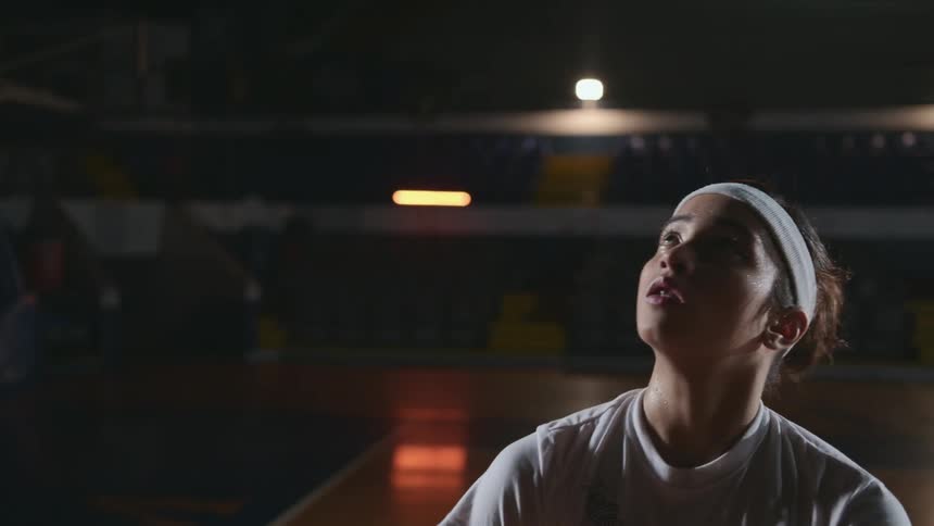 Teenage girl practicing basketball on an indoors court