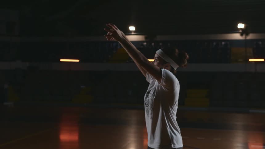 Teenager catches a basketball and then tosses it in a gym